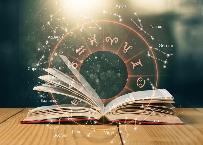 Open book on old wooden table with astrology illustration